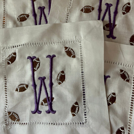 White cocktail napkins with purple 'W' and football patterns on a white background