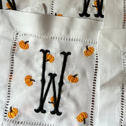 White fabric with black letter 'M' and small pumpkins pattern